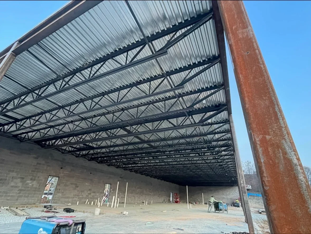Welded steel truss canopy with corrugated metal roof panels and structural support columns