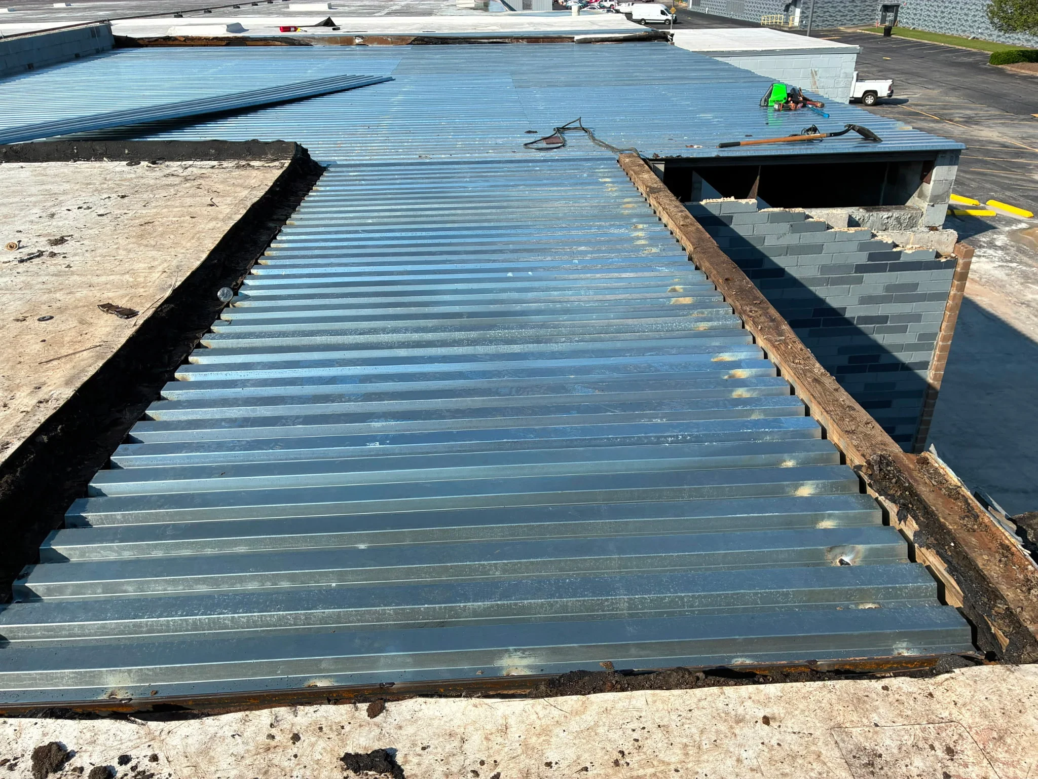 Blue corrugated metal roof deck panels installed on commercial building with concrete block perimeter walls